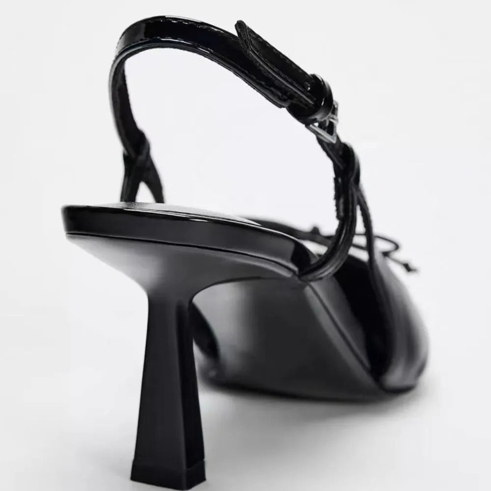 Patent leather bow with pointed tip thin heel and a shallow strap sandals